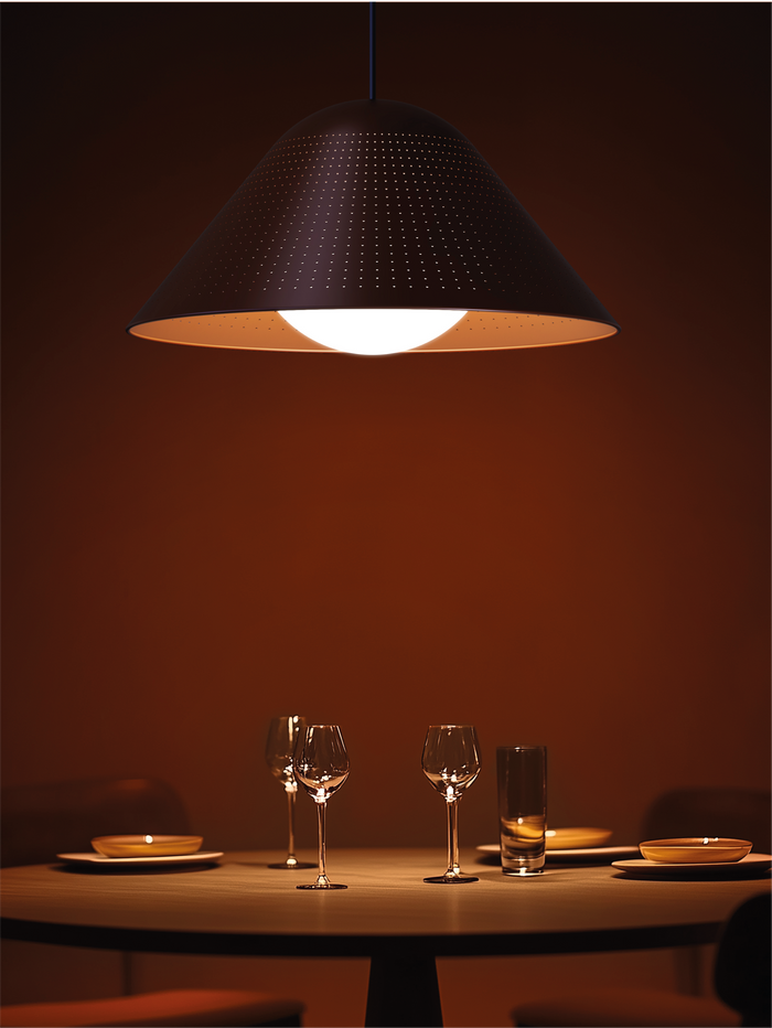 Dining table setting with wine glasses under a pendant light in a dimly lit room.