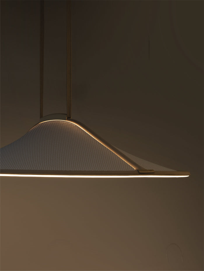 A modern pendant light with a wide, shallow conical shade made of textured white fabric, suspended by thin dark rods. The light is turned on, casting a warm glow along the bottom edge against a dark, minimalist background.