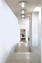 Modern hallway with white walls, a concrete floor, and ceiling lights.