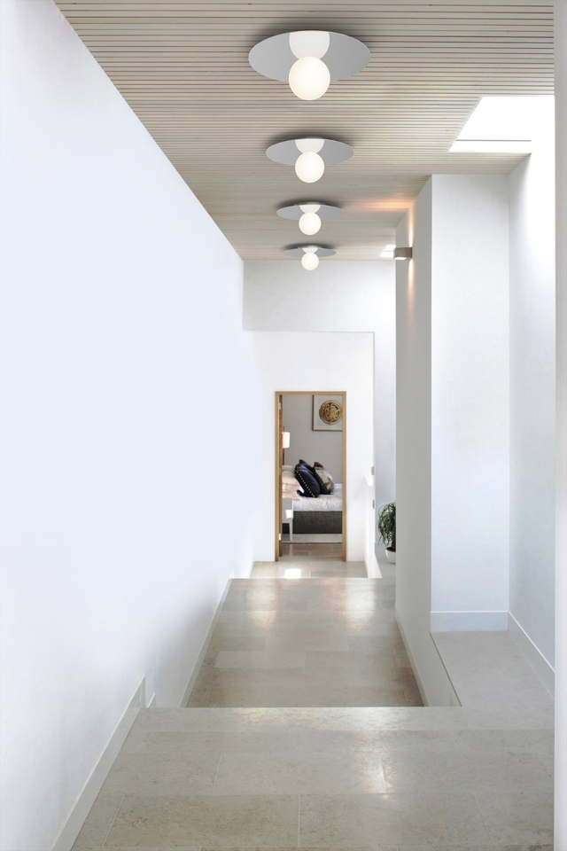 Modern hallway with white walls, a concrete floor, and ceiling lights.