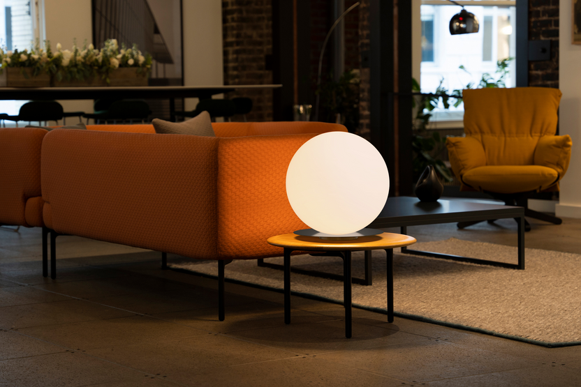 Modern living room with orange sofa, round table, and spherical lamp.