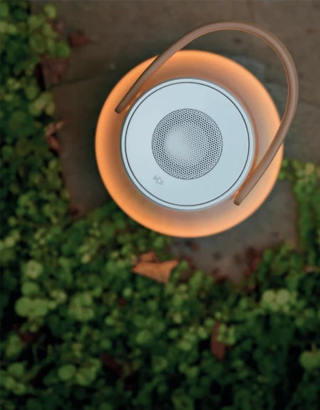Lantern-shaped speaker with a glowing orange light on a blurred green background