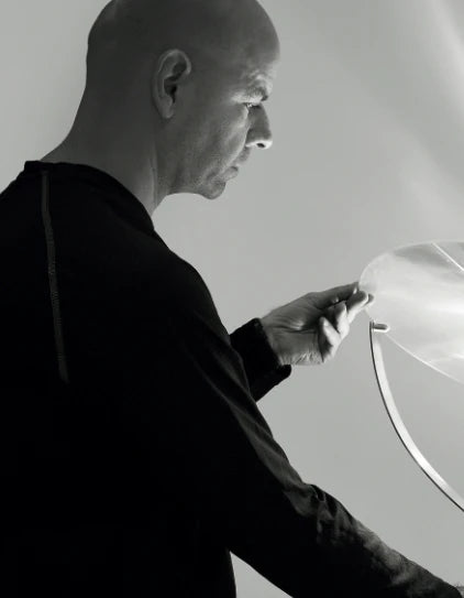 Person adjusting a large round white reflector against a neutral background