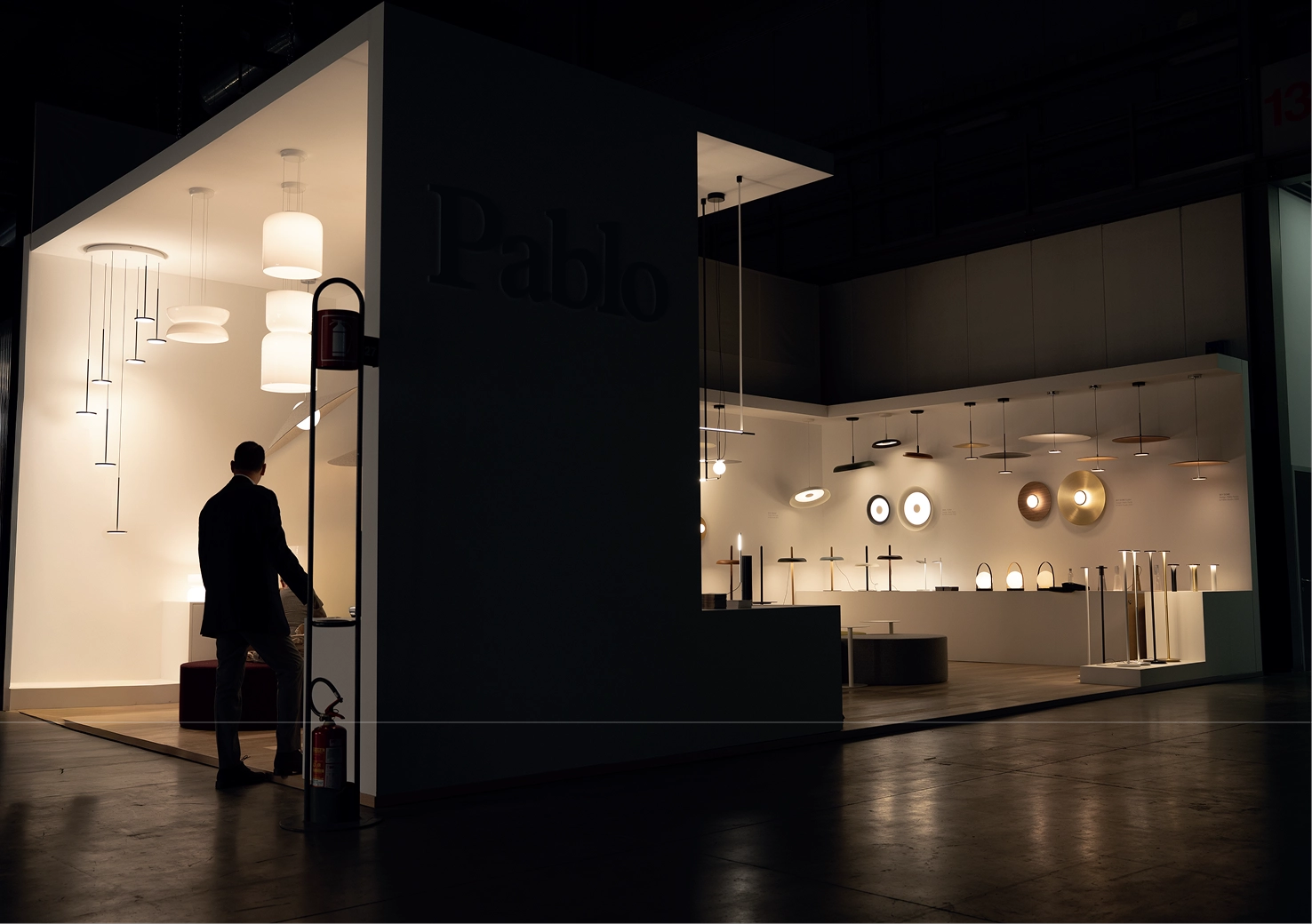 Modern interior design showroom with various lighting fixtures and a person observing them.